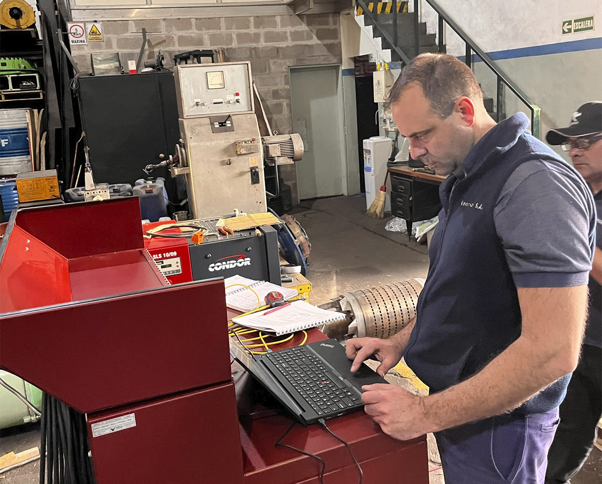 Técnico operando el equipo de ensayo de motores con una notebook en el taller de Electromecánica Koloczar
