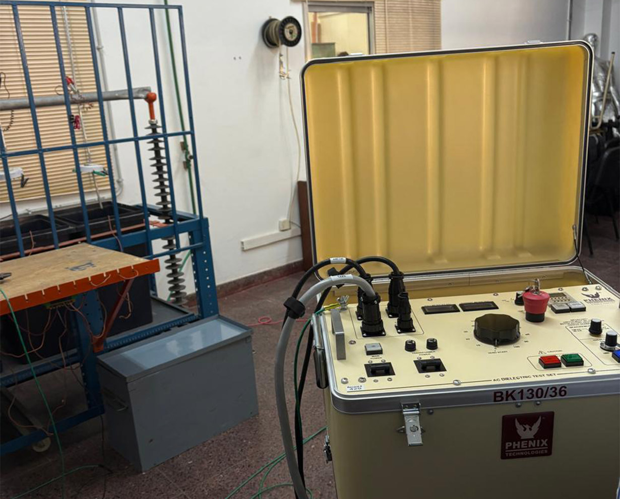 Equipo de ensayo dieléctrico Phenix BK130/36 con la tapa levantada, junto a la estructura de ensayo de aislación del laboratorio